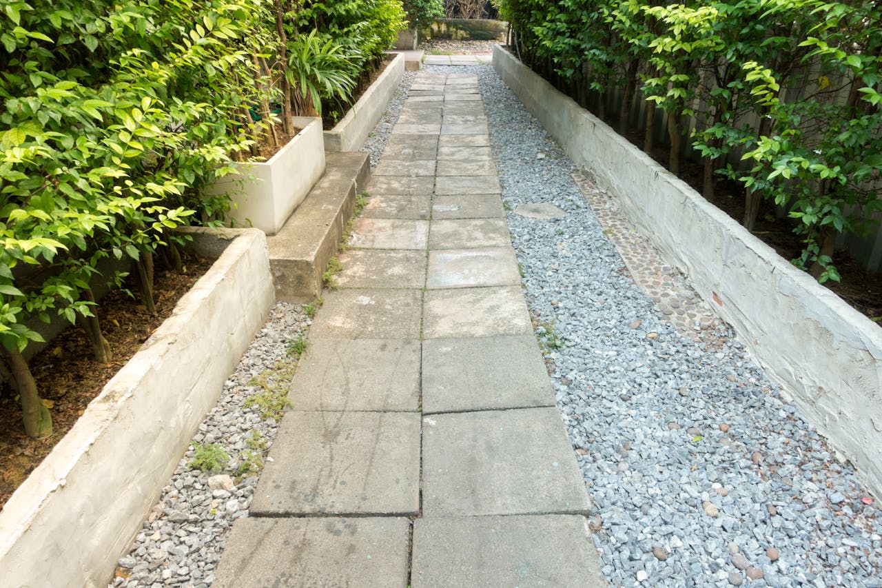 A tranquil garden path surrounded by lush green plants and a pebbled walkway.