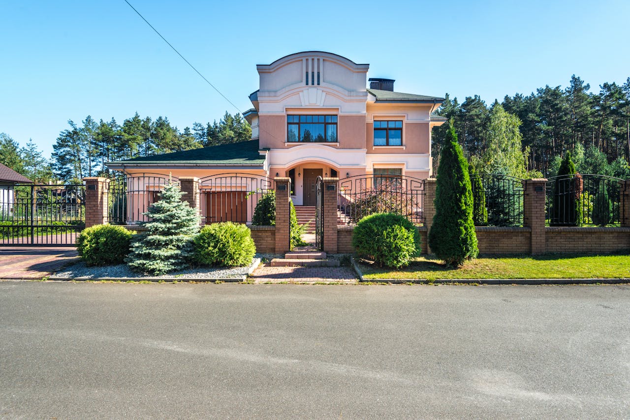 Beautiful luxury suburban house with landscaped garden and gated entrance on a sunny day.